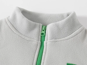 Detail of gray polar fleece jacket featuring a stand collar and green half-zipper