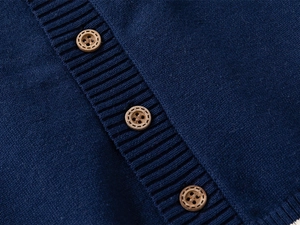 Close-up of navy knit cardigan featuring ribbed edge and vintage faux wood buttons