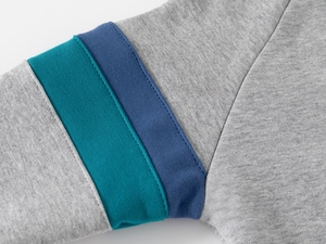 Gros plan des coutures à rayures contrastées et de la texture en maille du sweat gris
