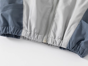 Détail de la veste d'hiver pour garçons avec patchwork gris-bleu et ourlet élastique