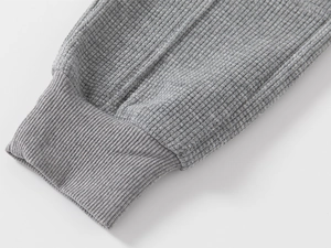 Détail macro du tissu gaufré gris avec poignets en maille côtelée pour pantalons de garçon