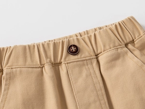 Detail of khaki cotton twill pants featuring elastic waistband and dark brown button accent