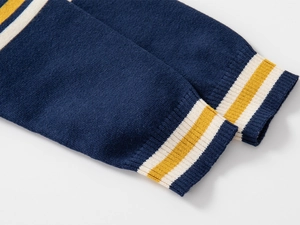 Detail of navy knit sweater sleeve with white and yellow ribbed striped cuff
