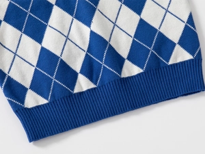Detailed close-up of blue and white argyle knit vest featuring ribbed hem stitching