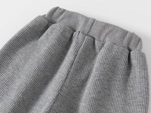 Détail du tissu gaufré gris et de la taille élastique côtelée d'un pantalon de sport garçon