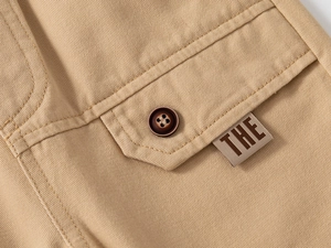 Detailed macro view of khaki cotton twill fabric with a button pocket and label