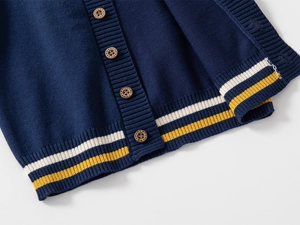 Detail of navy knit cardigan with wooden buttons and varsity striped hem for children