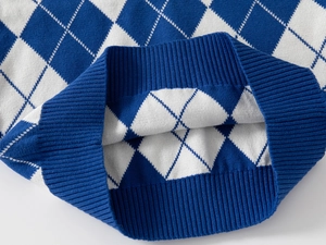 Close-up of blue and white argyle knit pattern and ribbed hem detailing on boys' sweater