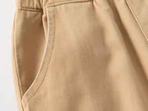 Detail of khaki cotton trousers featuring side pockets and precision stitching craftsmanship