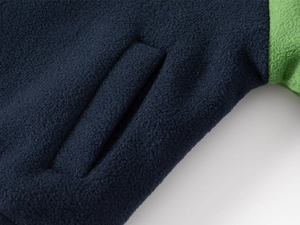 Detail of fleece jacket showing side slant pocket and navy green color block fabric