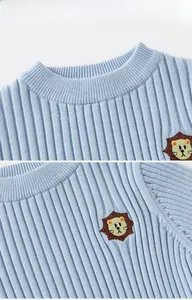 Detail of round ribbed neckline and cute lion embroidery on light blue knit sweater