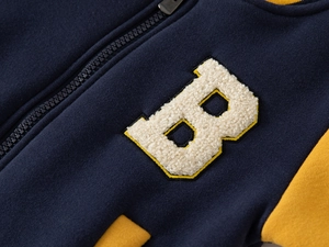 Close-up of chenille B-patch embroidery and metal zipper on kids' varsity jacket