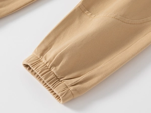 Detailed close-up of khaki cotton trousers cuff with ribbed elastic hem and twill texture