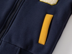 Detail of kids baseball jacket with navy fabric, yellow pocket, and chenille embroidery