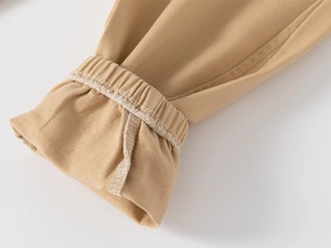 Detailed macro view of khaki cotton twill pants featuring elastic ribbed ankle cuffs