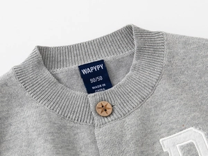 Gros plan du col de cardigan en tricot gris avec bouton étoile et texture côtelée