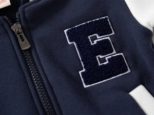 Close-up of navy blue baseball jacket with detailed white letter E towel embroidery
