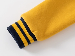 Close-up of navy blue ribbed cuffs with yellow stripes on a boy's baseball jacket