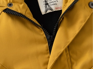 Détail de veste d'hiver jaune pour enfant avec fermeture éclair noire et étiquette de col