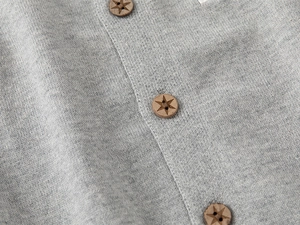 Détail du tissu en maille grise avec boutons ronds en bois ornés d'un motif d'étoile