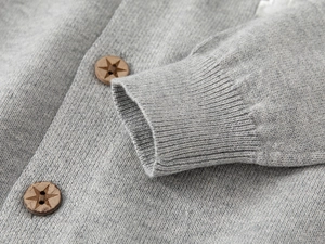 Détail du cardigan gris montrant les poignets côtelés et les boutons en bois étoilés