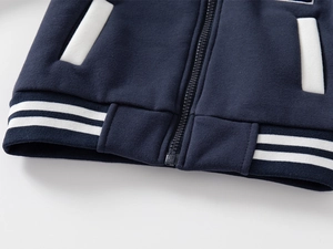 Detail of navy boy's baseball jacket showing white ribbed hem and smooth zipper closure
