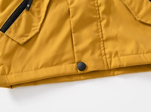 Détail de la veste à capuche enfant avec zip noir et tissu coupe-vent jaune gingembre
