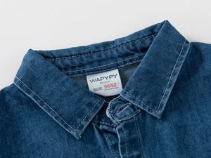 Macro del colletto di una camicia in denim blu scuro con cuciture bianche e luce soffusa
