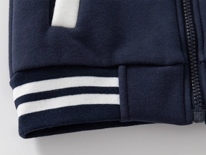 Detailed close-up of dark blue kids baseball jacket with ribbed hem and resin zipper