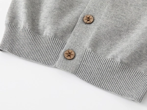 Détail du cardigan gris tricoté avec des boutons en bois aux motifs d'étoiles