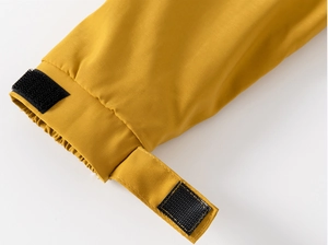 Détail du poignet de veste enfant jaune avec patte velcro réglable et bord élastique