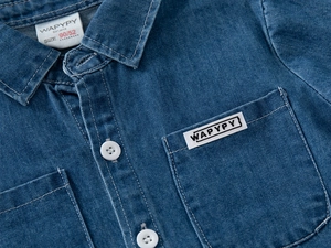 Dettaglio della camicia di jeans per bambini con colletto classico e bottoni bianchi fini