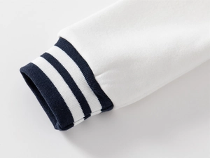 Detail of navy blue ribbed cuffs with white stripes on a premium white baseball jacket