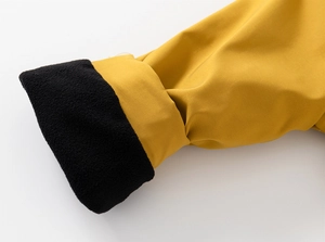 Gros plan détaillé du tissu extérieur jaune coupe-vent et de la doublure polaire noire épaisse