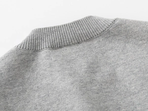 Détail de l'encolure ronde côtelée et de la texture en maille fine du pull gris pour enfant