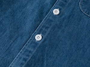 Dettaglio macro di camicia in denim per bambini con trama twill e bottoni bianchi