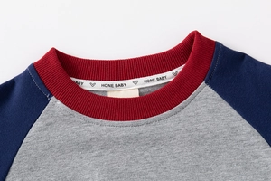 Detail of baby raglan sweatshirt with red ribbed neckline and HONE BABY brand label