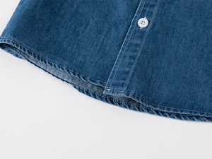Dettaglio dell'orlo curvo e bottoni bianchi su camicia in denim blu scuro per bambini