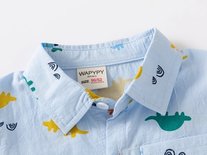Détail du col d'une chemise bleue pour bébé avec motifs dinosaures et étiquette