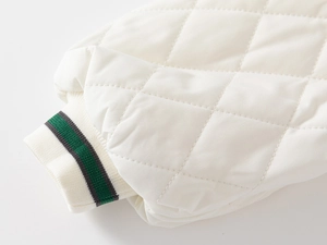 Detail of white diamond quilted fabric and striped ribbed cuffs on children's jacket