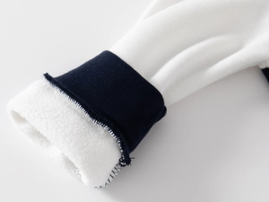 Detail of navy blue ribbed cuffs and warm white fleece lining on boy's baseball jacket