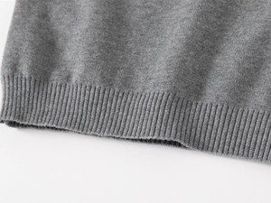 Vue macro d'un pull gris montrant l'ourlet côtelé de qualité et la texture du tricot