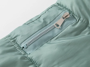 Close-up of a silver metal zipper on sage green quilted winter jacket for kids