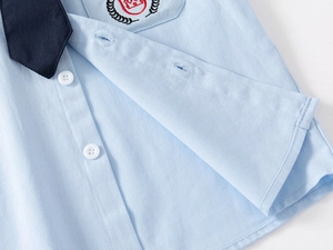 Detail of light blue boys shirt with navy tie and crown embroidery on the pocket