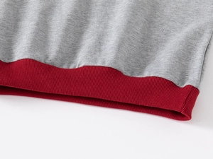 Detailed view of the gray knit fabric and red ribbed hem on kids' oversized sweatshirt