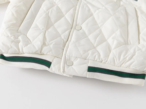 Detail of white diamond-quilted kids jacket with striped ribbed hem and snap buttons