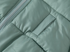 Close-up of a child puffer jacket in bean green with quilted zipper and pocket details