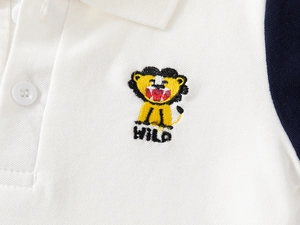 Detailed macro of kids' white polo shirt with lion embroidery and navy sleeve cuff