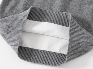 Détail d'un pull en tricot gris foncé montrant l'ourlet côtelé et la doublure blanche