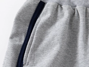 Close-up of kids grey sweatpants with elastic waistband and navy side tape detail